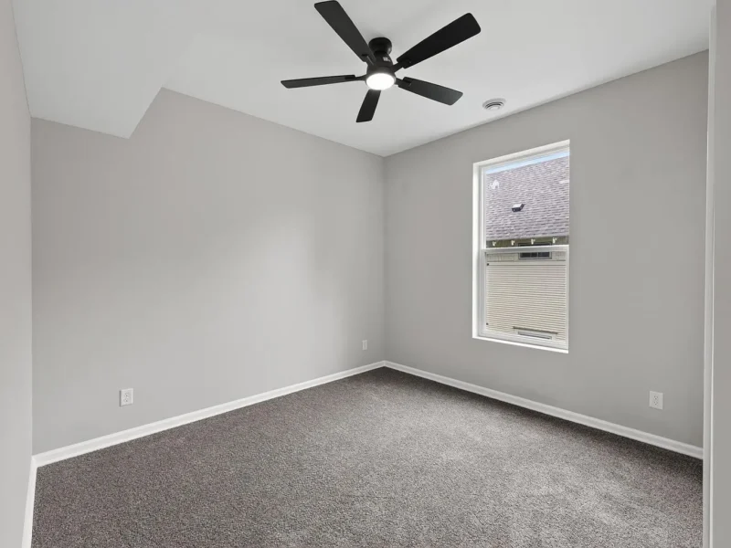 Carpeted bedroom with a ceiling fan