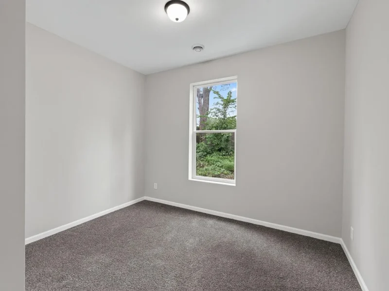 Carpeted bedroom with a single window