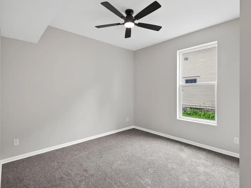 Carpeted bedroom with a ceiling fan and a window