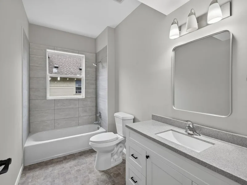 Bathroom with a tiled tub surround and a quartz vanity