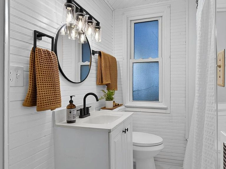 Bathroom with a shiplap wall, round mirror and a vanity