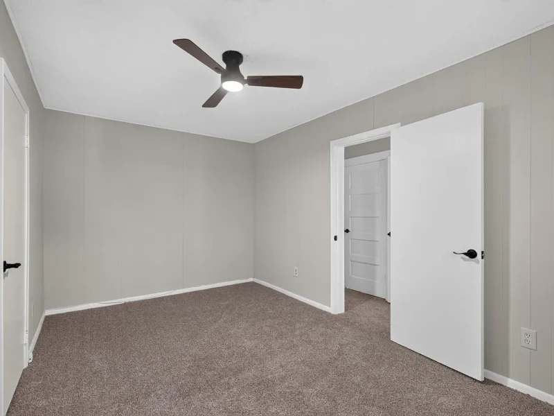 Carpeted bedroom with a ceiling fan and two doors