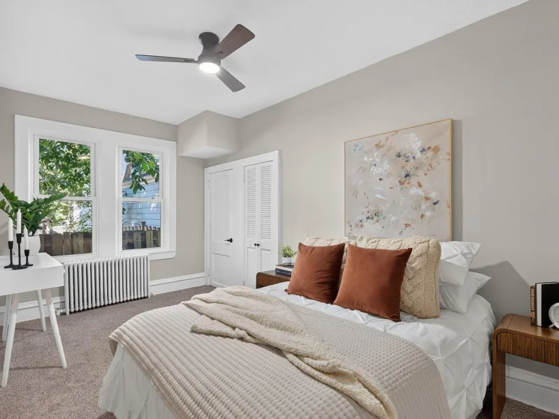 Carpeted bedroom with a ceiling fan and a desk under the window