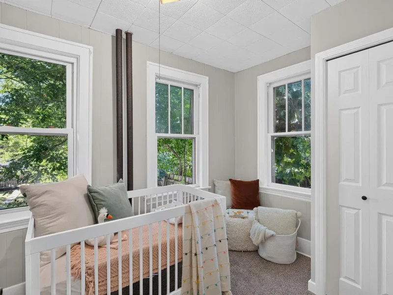Corner bedroom with windows on two walls, set up as a nursery