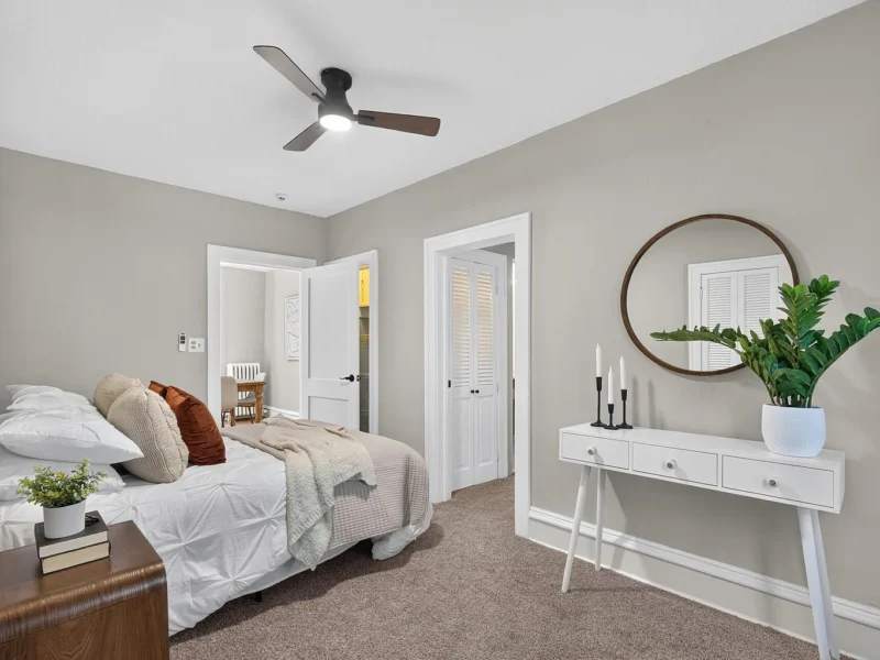 Carpeted bedroom with a ceiling fan and a mirrored console table