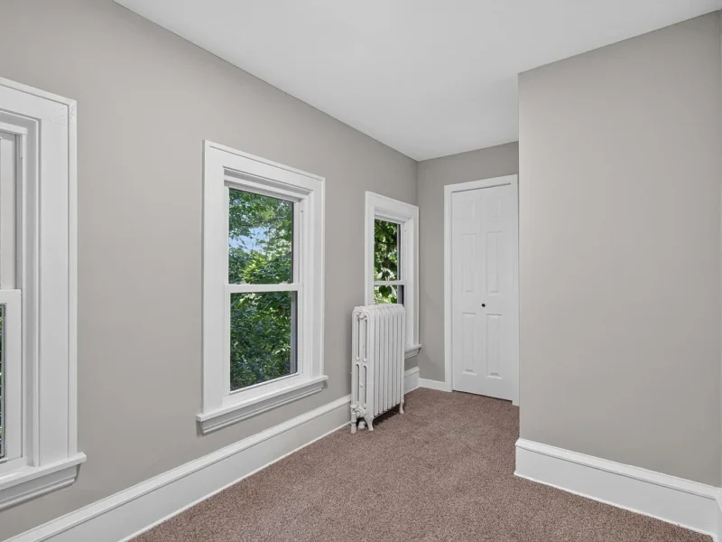 Carpeted bedroom with a radiator under the window