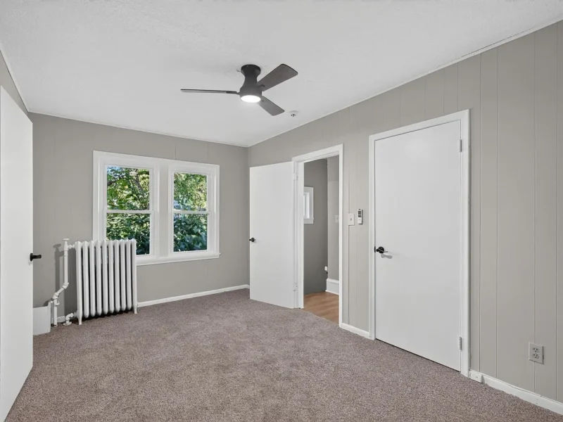 Carpeted bedroom with a ceiling fan and a closet door