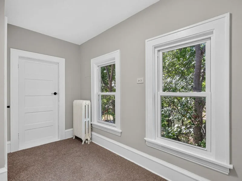 Carpeted bedroom with two windows and a radiator