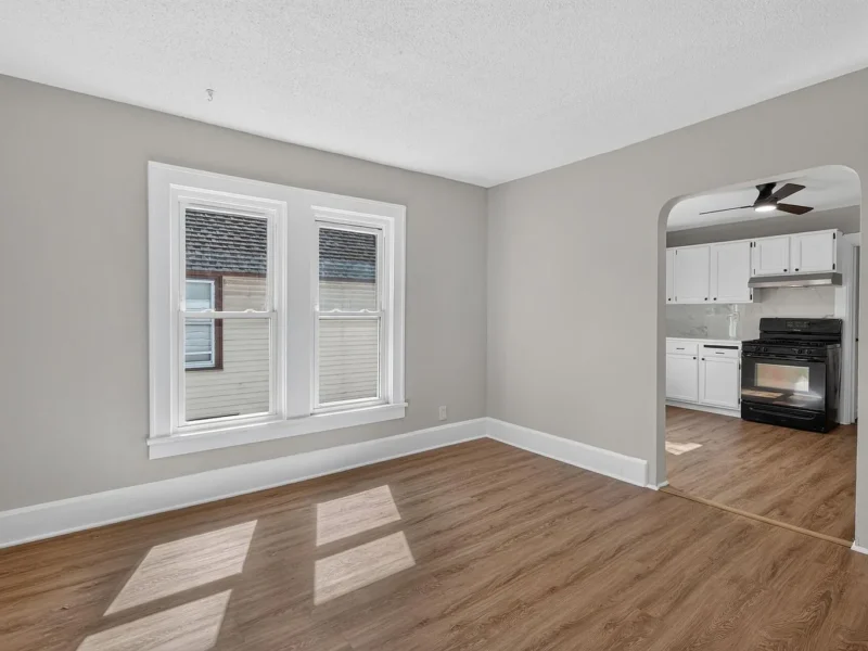 Room with hard-surface flooring looking through an arch to the kitchen