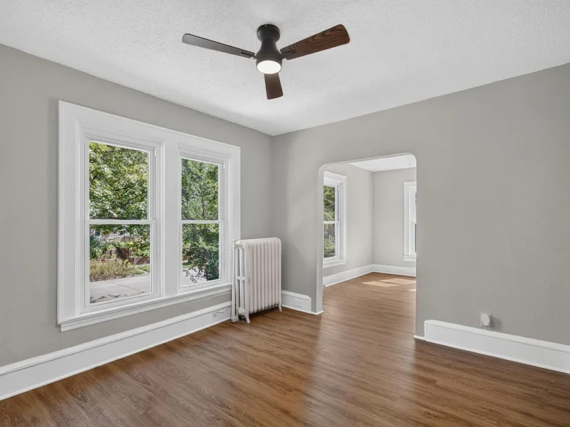 Empty room with hard-surface flooring, a radiator and two windows