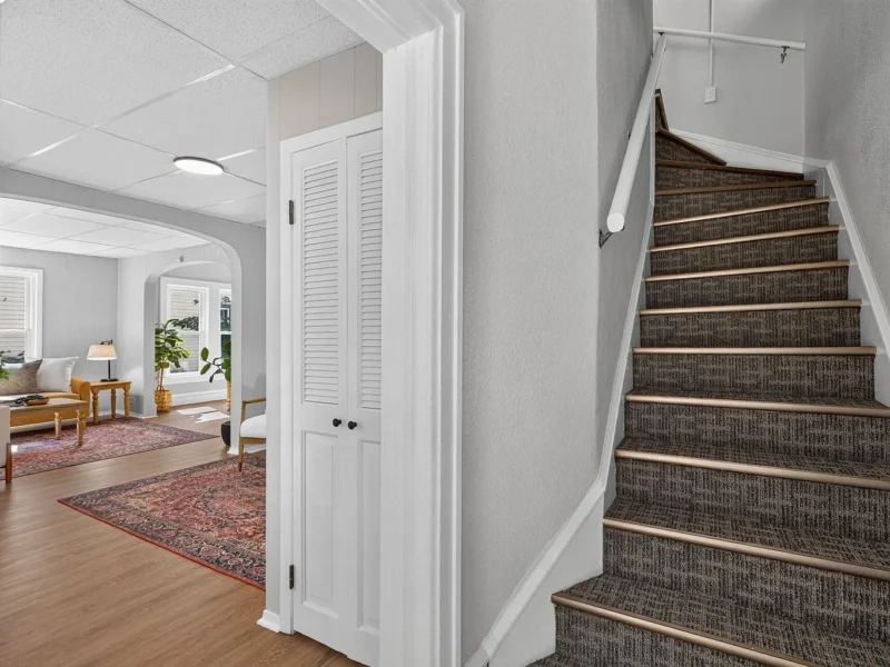 Staircase to the upper level beside a closet door