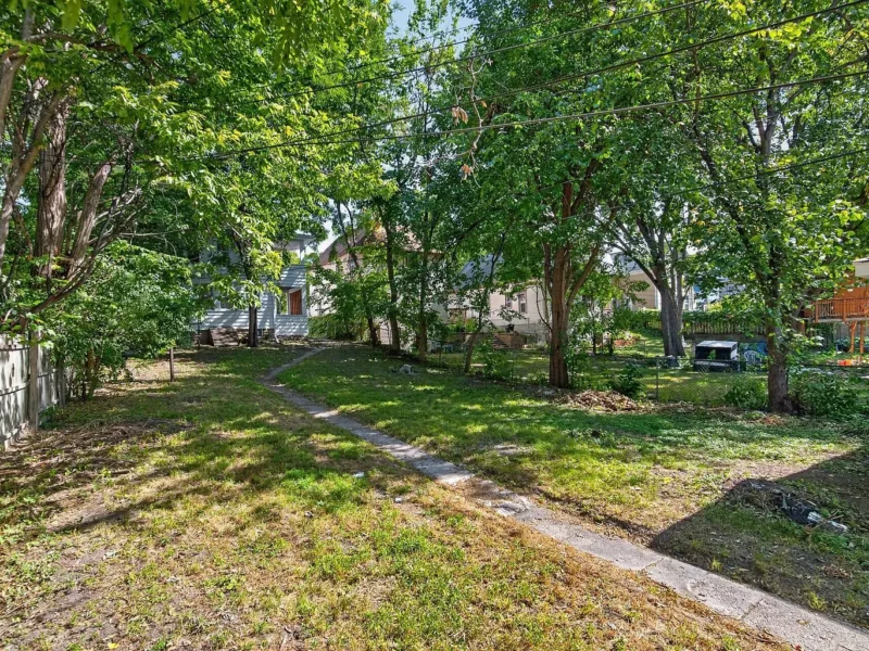 Back yard with mature trees and a walkway