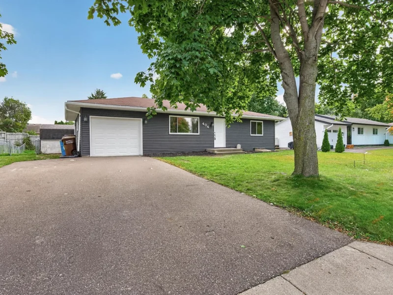 Driveway leading to the attached garage under a large shade tree