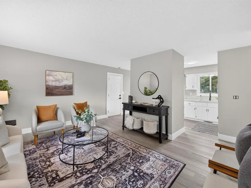 Living room with a patterned rug, two armchairs and a round glass coffee table