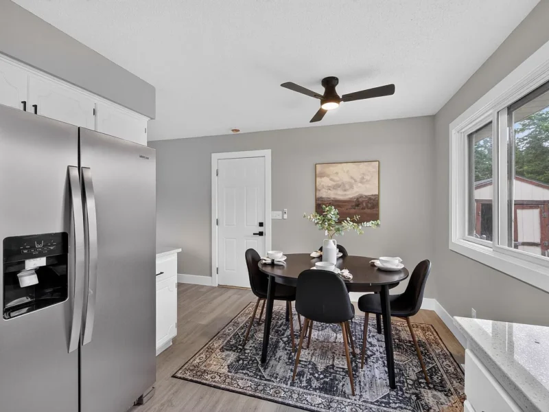 Dining area beside a stainless steel refrigerator