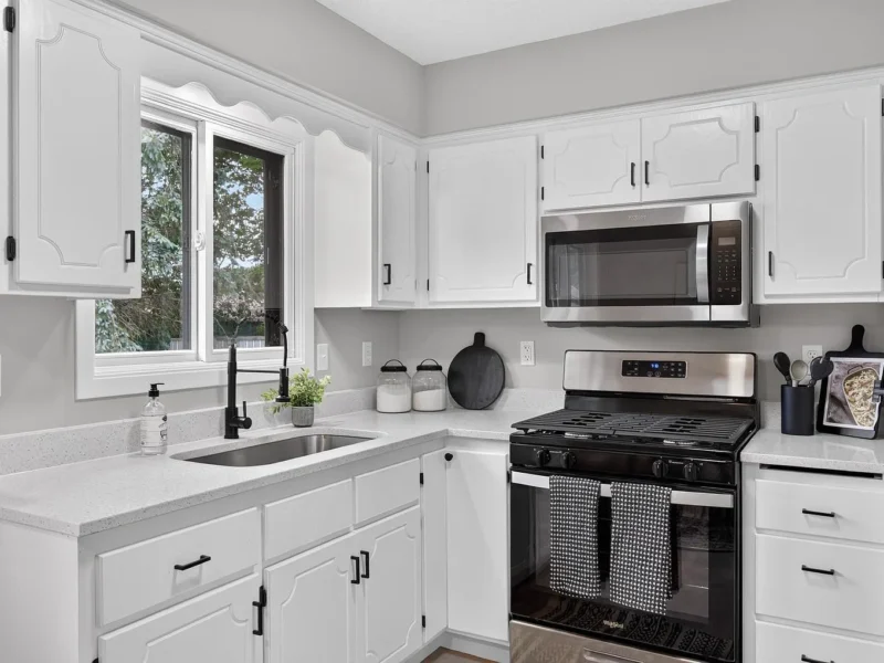 Kitchen with white cabinets, black hardware and a stainless steel range