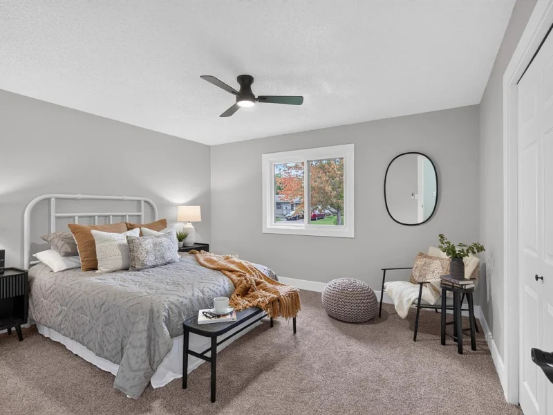 Carpeted bedroom with a white metal bed frame and a ceiling fan