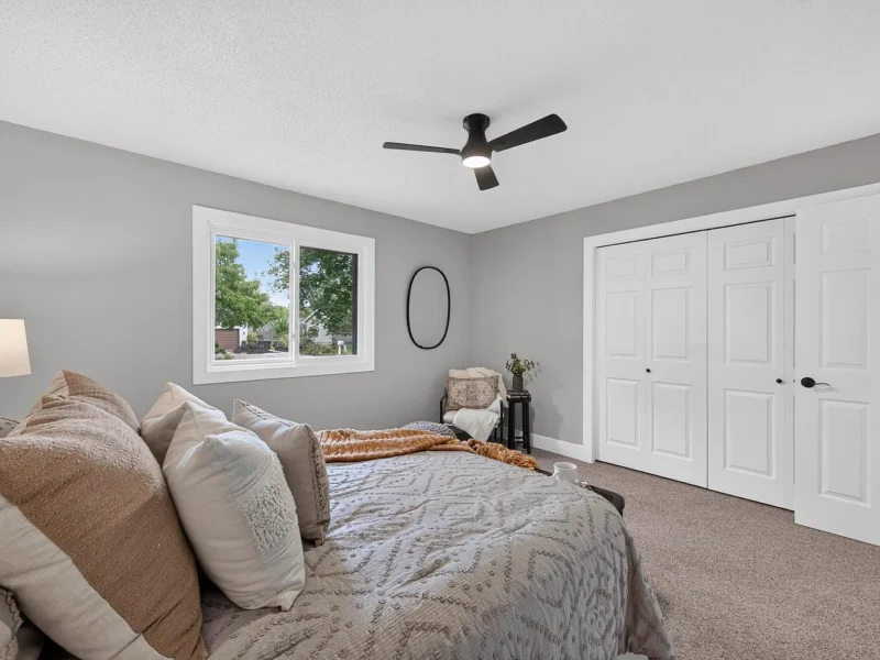 Bedroom with a ceiling fan, a window and white closet doors
