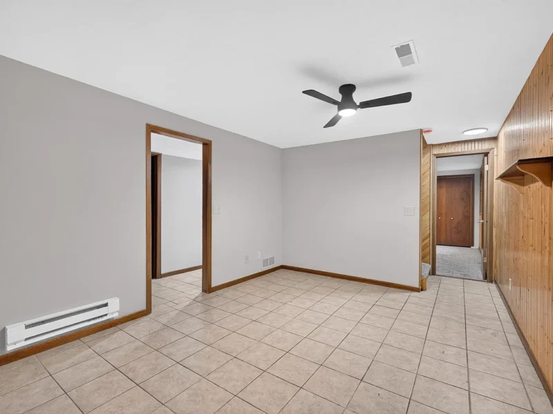 Lower-level room with tile flooring and wood-paneled walls