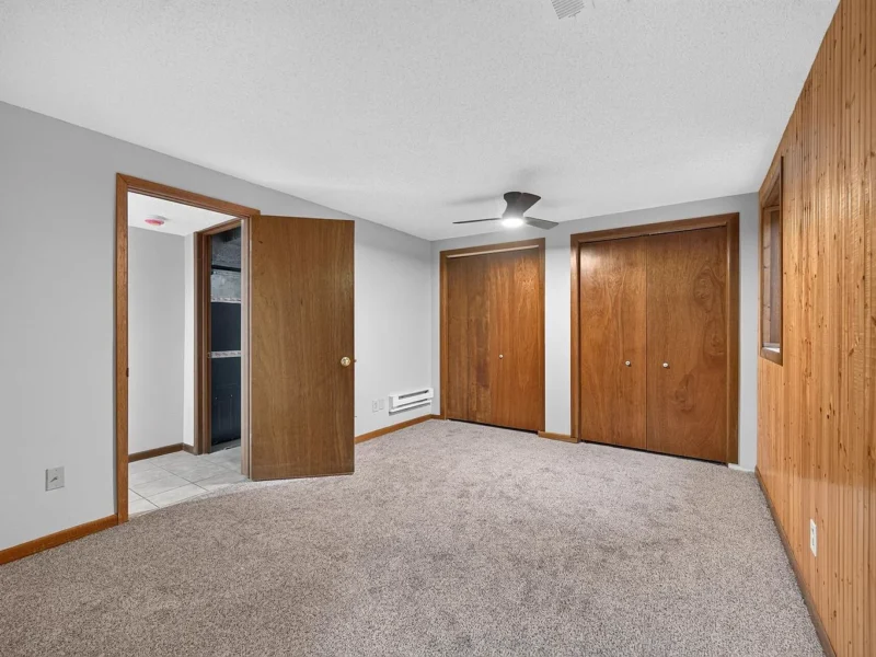 Lower-level carpeted room with wood doors and paneling