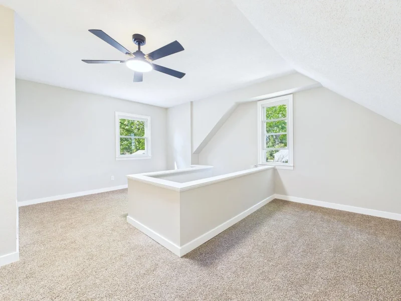 Upstairs room with two dormer windows and carpet
