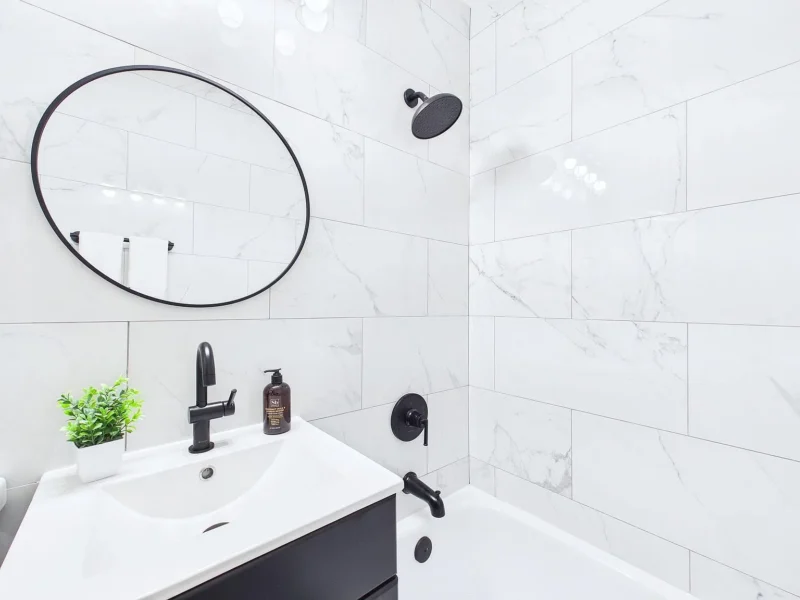 Bathroom with a round mirror and marble-look tile