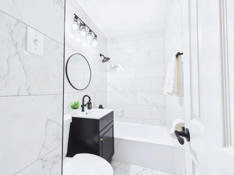 Bathroom with a tub, round mirror and black fixtures