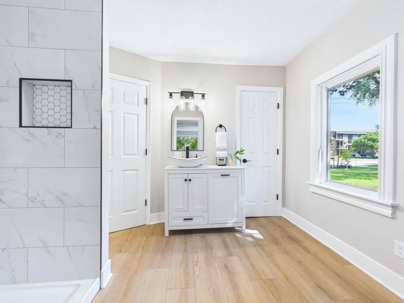 Bathroom with a tiled shower, vanity and window